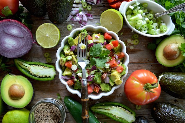 A balanced meal is one of the many natural remedies for menopause symptoms. As seen here: Ahearty salad surrounded by vegetables on a rustic table top. 